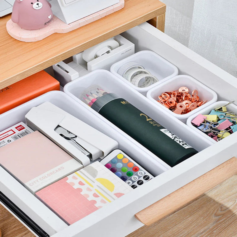 Organized desk drawer with stationery items on a wooden desk.