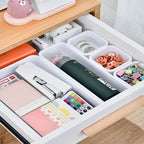 Organized desk drawer with stationery items on a wooden desk.