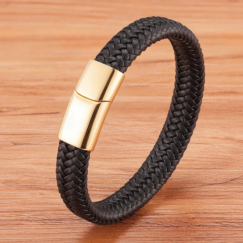 Black braided bracelet with a gold clasp on a wooden surface
