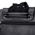 Close-up of a black leather bag with a zipper and strap on a white background