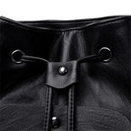 Close-up of a black leather drawstring bag with metal loops and buttons.