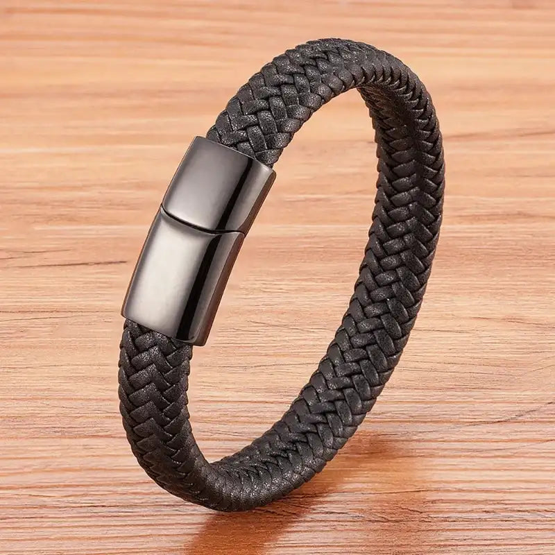 Black braided bracelet with a metallic clasp on a wooden surface