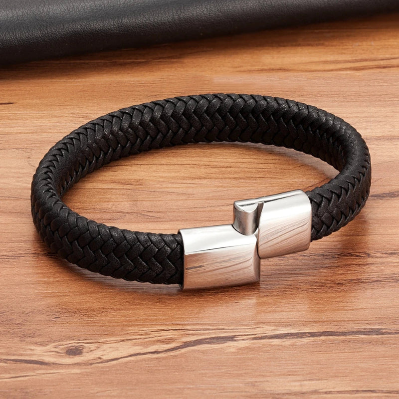 Black braided leather bracelet with a silver clasp on a wooden surface