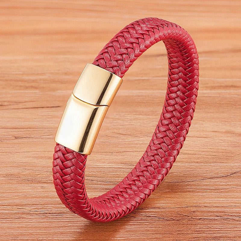 Red braided bracelet with a gold clasp on a wooden surface