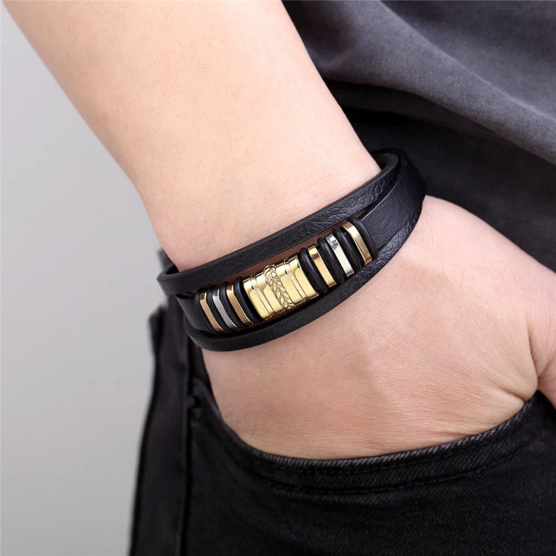 Black leather bracelet with gold and silver accents on a wrist against a neutral background