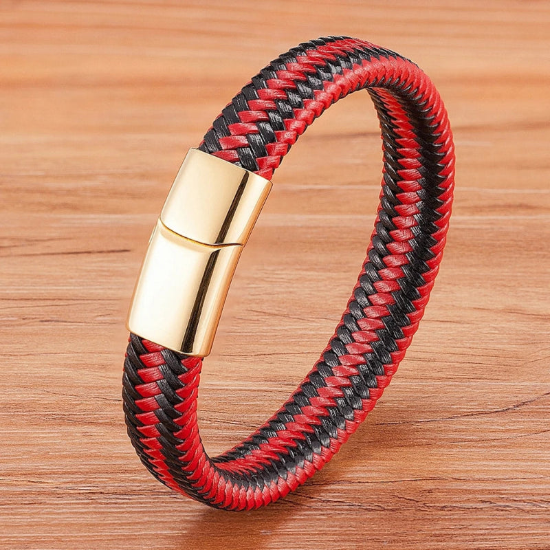 Red and black braided bracelet with a gold clasp on a wooden surface