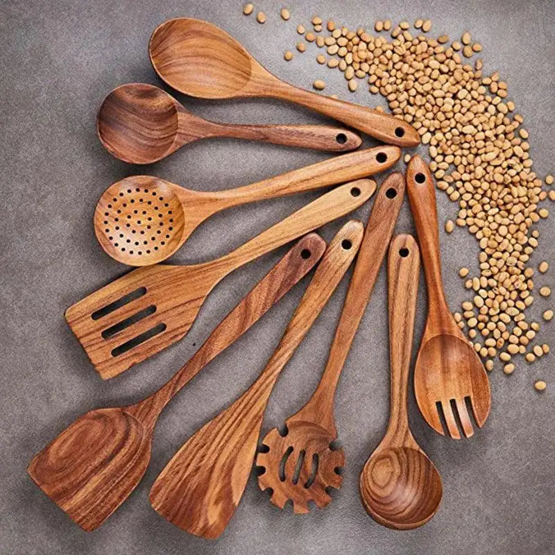 Set of wooden kitchen utensils on a gray surface with scattered lentils.