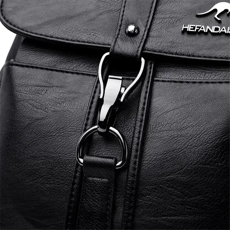 Close-up of a black leather bag with a silver zipper and brand logo.