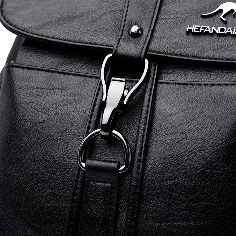 Close-up of a black leather bag with a silver zipper and brand logo.