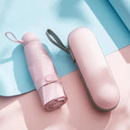 Pink umbrella and its case on a light blue and pink background