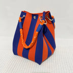 Blue and orange striped bag with handle on a textured white background