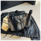 Patterned bag with black strap on a black leather jacket