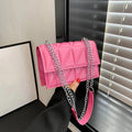 Pink handbag with a chain strap held by a person against a neutral background