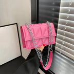 Pink handbag with a chain strap held by a person against a neutral background