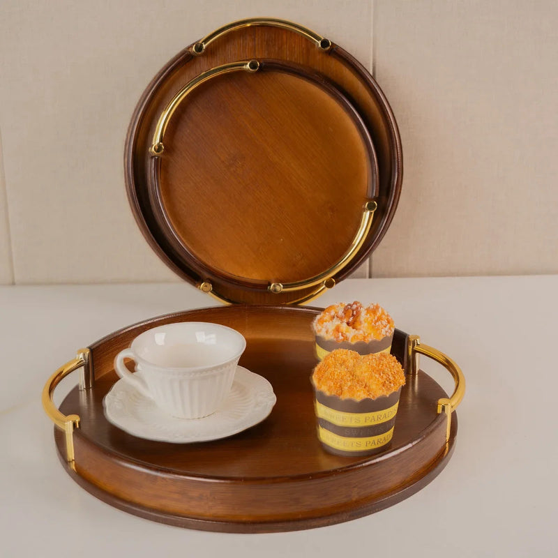 Wooden tray with a cup, saucer, and two cupcakes on a beige background