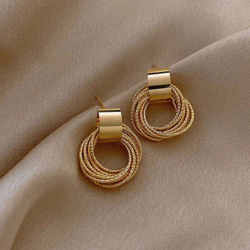 Gold hoop earrings on a beige fabric background