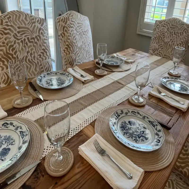 Dining table set with plates, glasses, and cutlery on a wooden table.