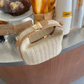 Woven handbag on a wooden surface with a blurred background