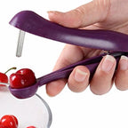 Purple cherry pitter being used to remove a cherry from a hand