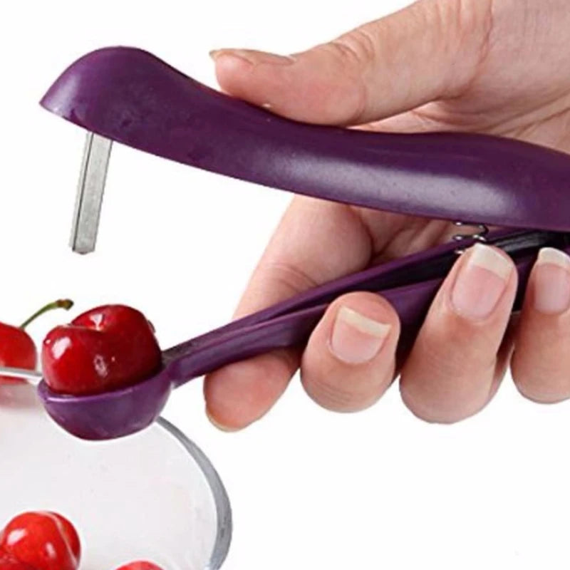 Purple cherry pitter being used to remove a cherry from a hand