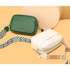 Two crossbody bags, one green and one beige, on a beige background.