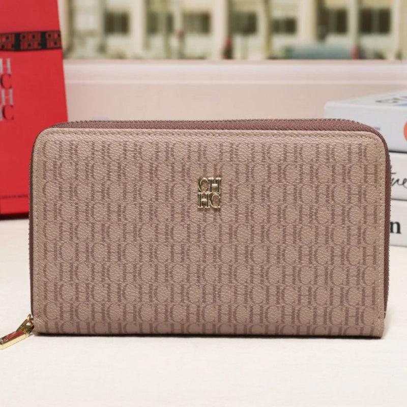 A beige monogram zip-around wallet with a gold-tone logo emblem, displayed on a white surface with a blurred city street background.