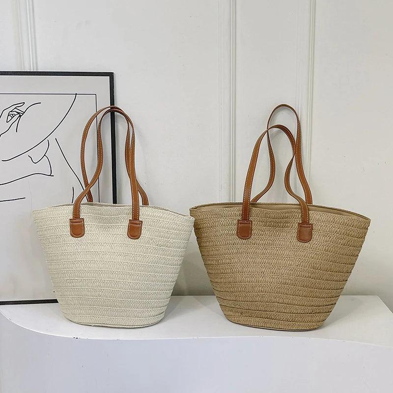 Two straw bags with brown handles on a white surface.