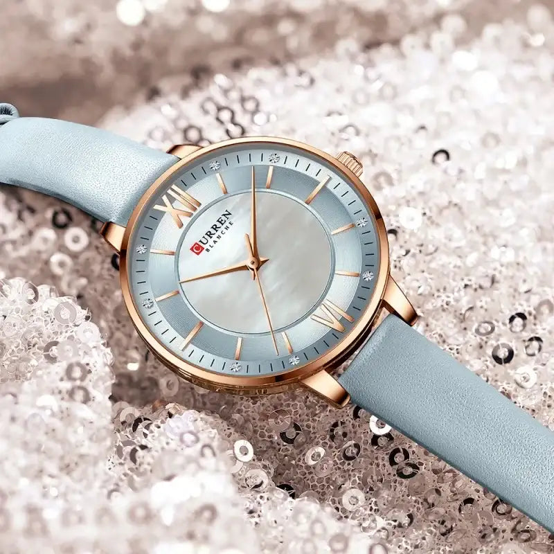 Wristwatch with light blue strap and rose gold case on a textured background