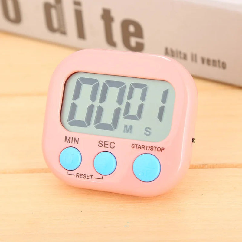 A pink digital kitchen timer with a light blue-green LCD display showing 00:01, featuring three light blue buttons labeled MIN, SEC, and START/STOP, placed on a light wood surface.