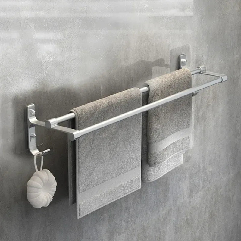 Towel rack with two gray towels and a white scrubber on a gray tiled wall.