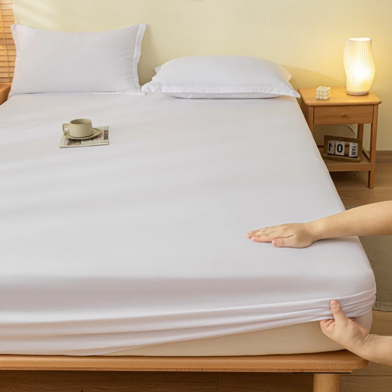 Person stretching a fitted sheet over a bed with a nightstand in the background.