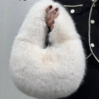 White fluffy bag held by a person wearing a black coat with white buttons against a gray background.