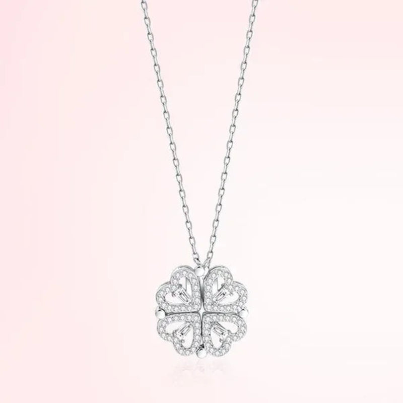 Silver four-leaf clover pendant necklace on a light pink background