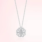 Silver four-leaf clover pendant necklace on a light pink background