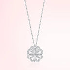Silver four-leaf clover pendant necklace on a light pink background
