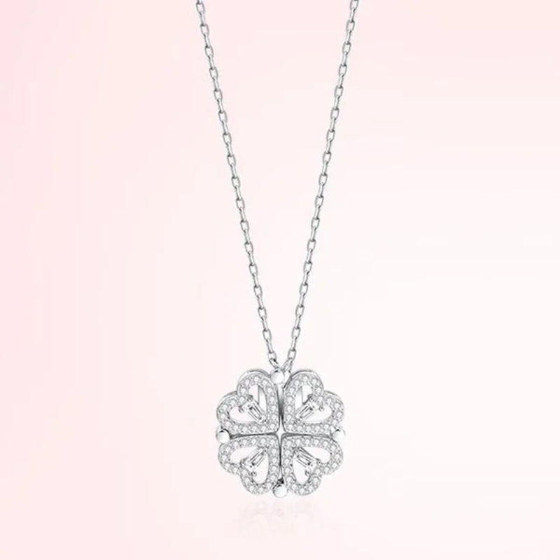Silver four-leaf clover pendant necklace on a light pink background