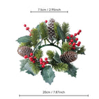 An artificial Christmas wreath with pine branches, green holly leaves, brown pinecones, and red berries, shown with measurement lines indicating a width of 20cm (7.87 inches) and a height of 7.