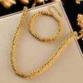 Gold necklace and bracelet set on a white box with gold decorative elements.