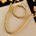 Gold necklace and bracelet set on a white box with gold decorative elements.