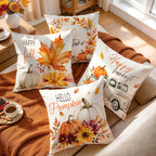 Four decorative throw pillows with autumn watercolor designs are arranged on a beige sofa with a rust-colored blanket. The pillows feature fall leaves, pumpkins, flowers, and phrases like 'Happy fall,' 'turn of the year,' 'Happy harvest,' and 'Hello Pumpkin.