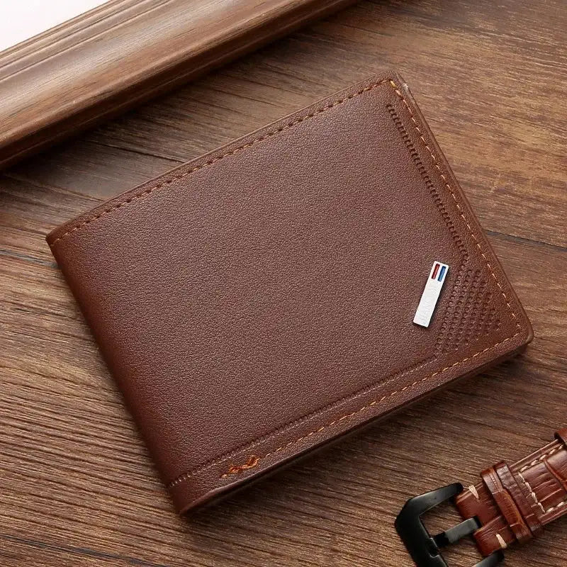Brown leather wallet with a strap on a wooden surface
