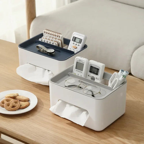 White and blue storage box on a wooden table with various items including a plate of cookies.