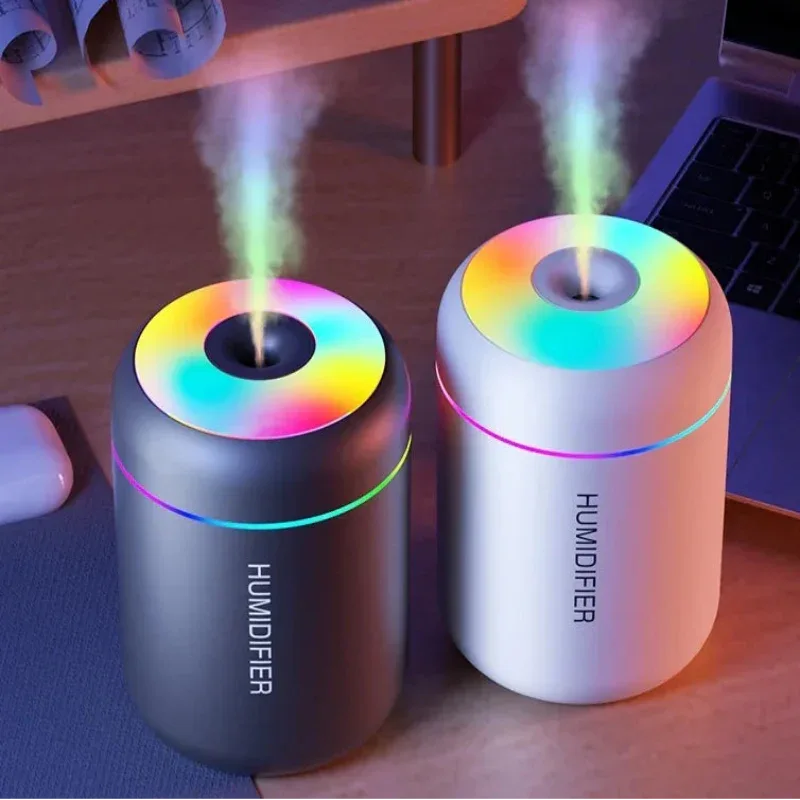 Two colorful humidifiers on a desk with a laptop and mouse in the background.