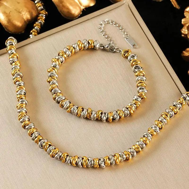 Gold and silver beaded necklace and bracelet set on a beige surface