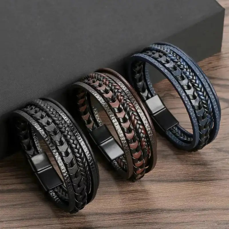 Three braided leather bracelets on a wooden surface with a dark gray background
