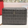 A dark gray leather zip-around wallet with an allover embossed monogram pattern and a small gold-tone logo at the center front, displayed on a white surface with a blurred urban window view in the background.