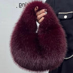 Maroon faux fur scarf held by a person against a plain background