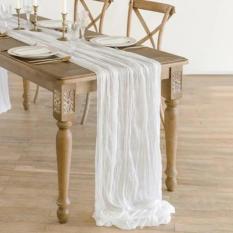 Dining table set with a white table runner and wooden chairs in a room.