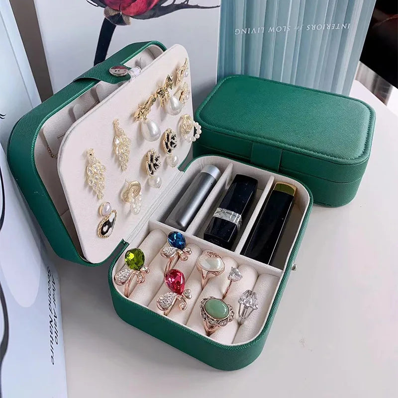 Green jewelry case with rings, earrings, and lipsticks on a white surface