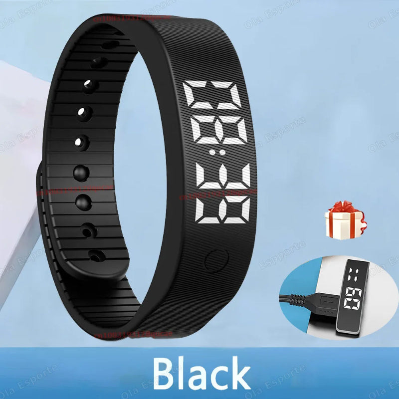 Black digital fitness tracker with charging cable on a blue background
